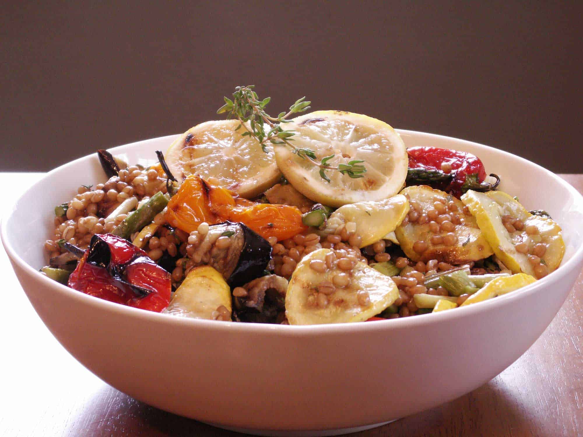 Grilled vegetable and wheat berry salad in white bowl.