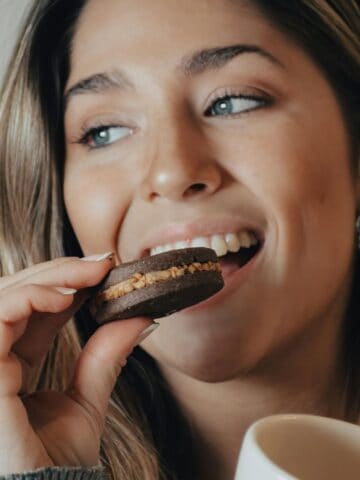 woman snacking on a cookie with a mug.