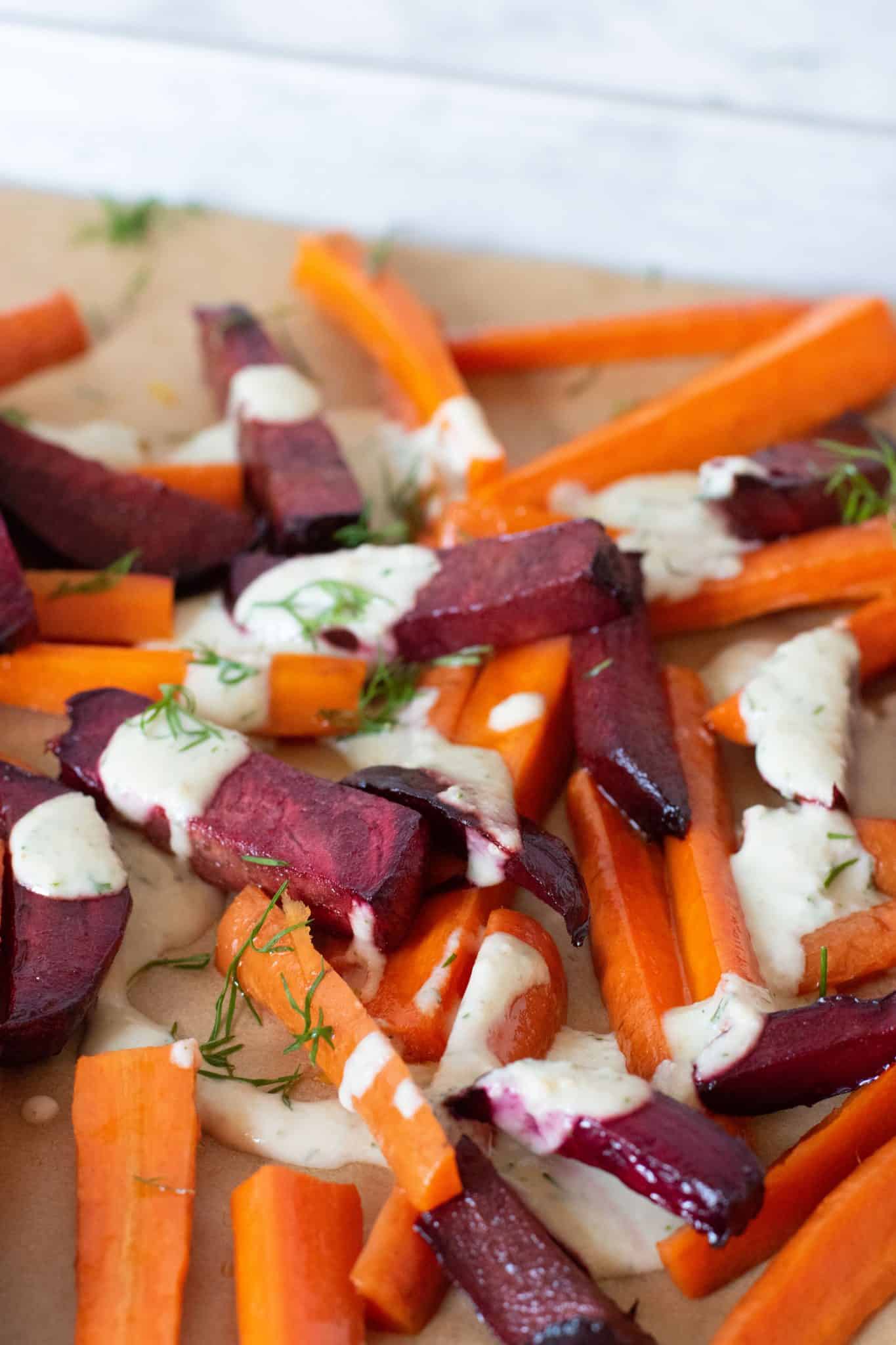 Roasted Beets and Carrots on a baking sheet, drizzled with garlic dill sauce