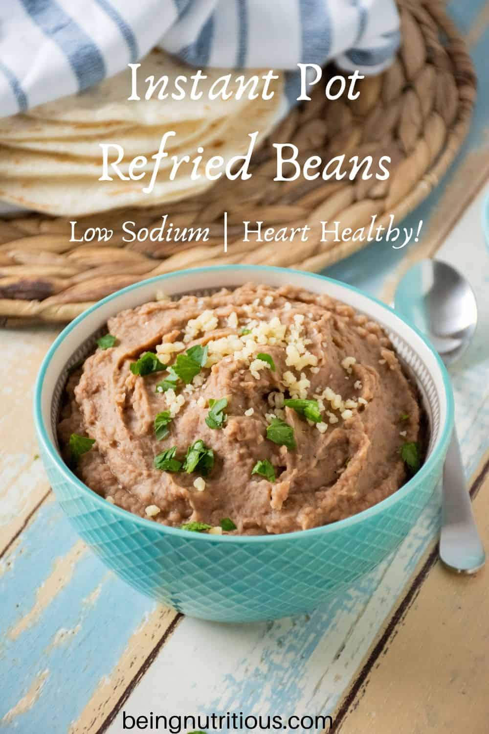 Bowl of refried beans with tortillas in the background.