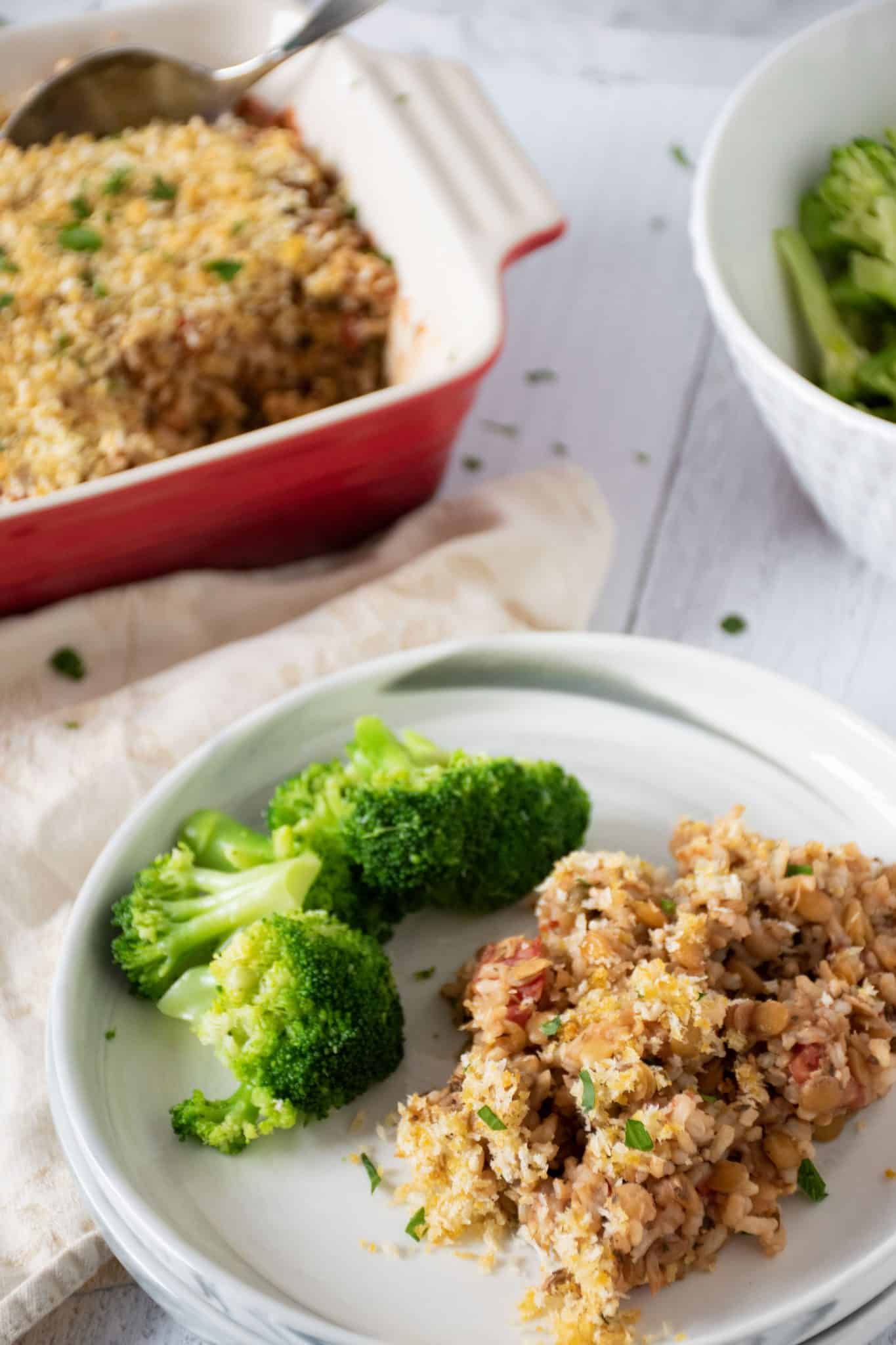 A scoop of Italian Lentil & Rice casserole on a plate with steamed broccoli.