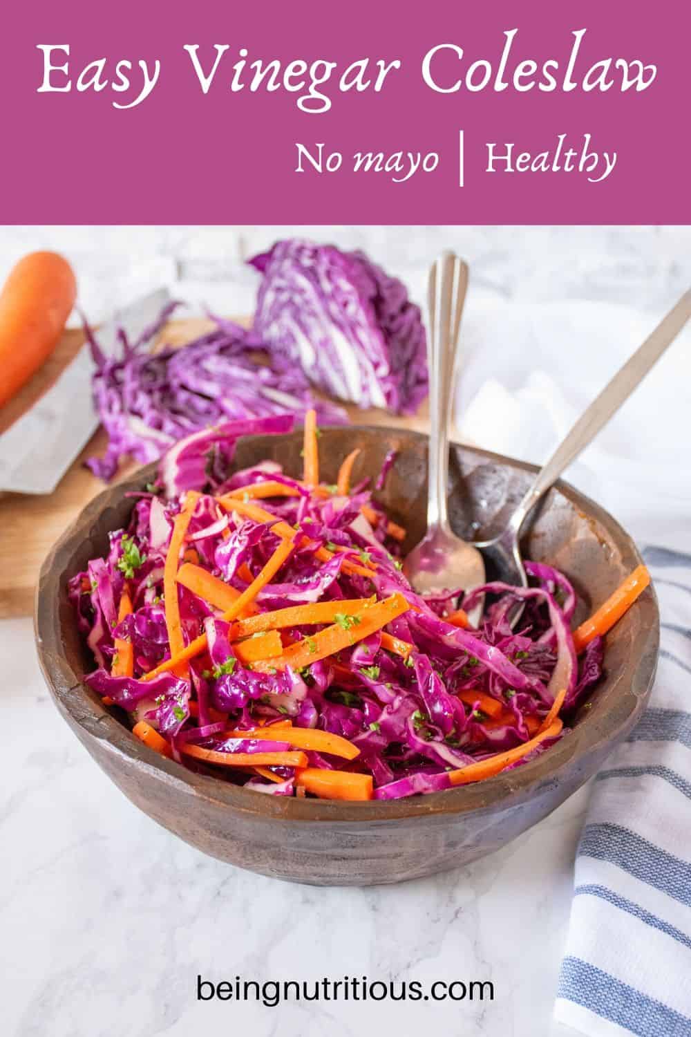 Easy vinegar coleslaw, in a wooden bowl, with shredded purple cabbage on a cutting board visible in the background.