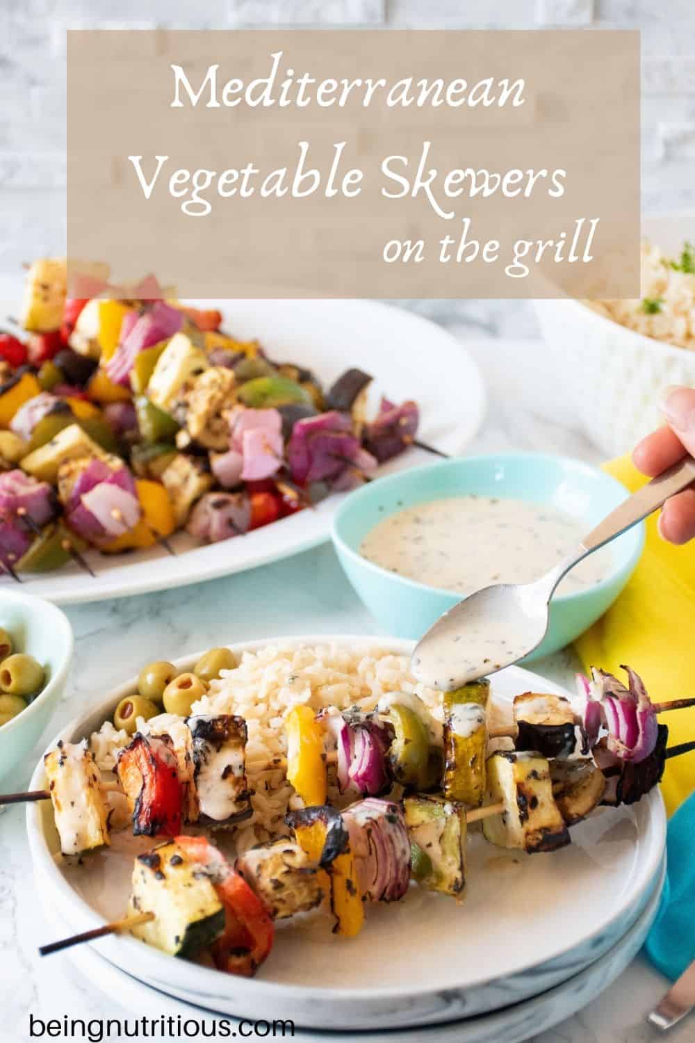 Plate with 2 veggie skewers and rice, with dressing being drizzled over. Text overlay: Mediterranean Vegetable Skewers on the grill.