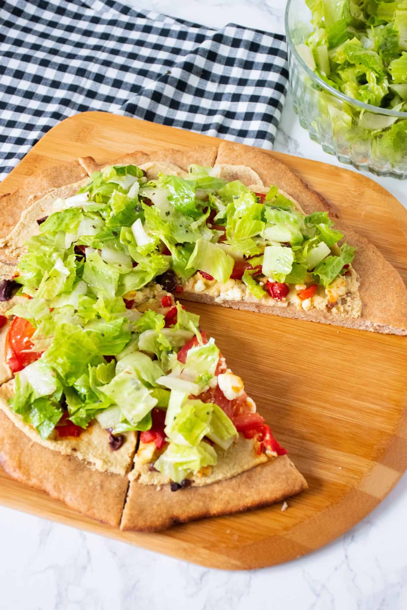 Pizza on a peel, with whole wheat crust, topped with salad.