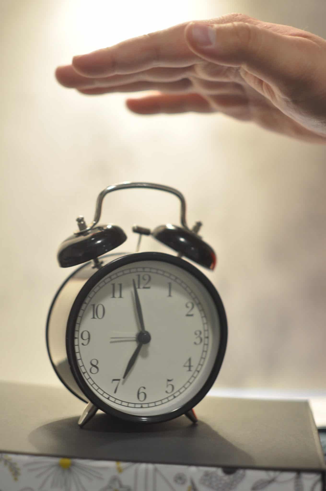 A hand turning off an alarm clock.