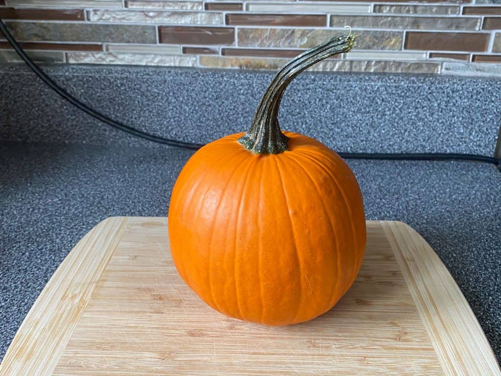 Small pie pumpkin on a cutting board.