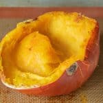Baked pumpkin half, face up on baking sheet.