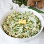 Bowl of mashed potatoes with a pat of butter on top. Text overlay: Healthy Colcannon (Irish mashed potatoes with kale).