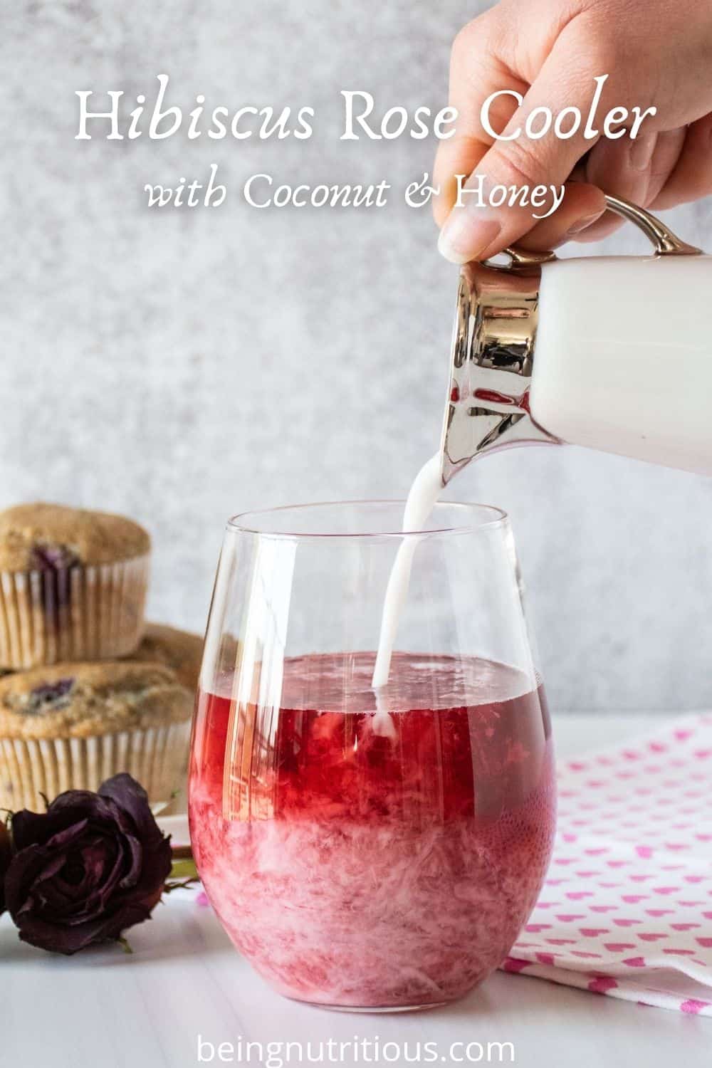 Glass of red tea with coconut milk being poured in. Text overlay: Hibiscus Rose Cooler with Coconut & Honey.