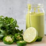 Small jar of green sauce, with ingredients around it.