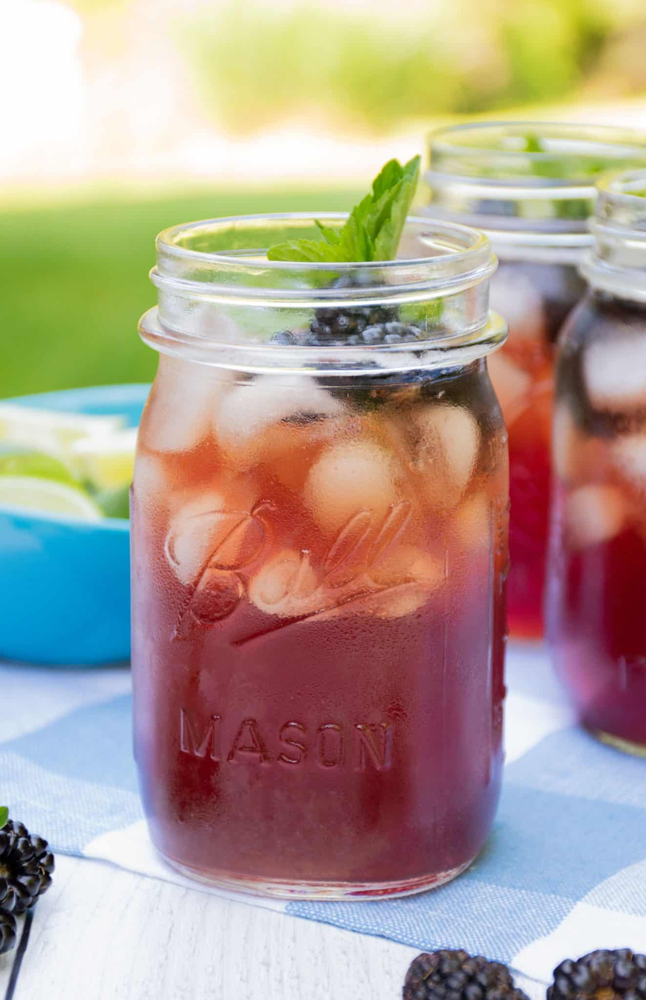 Iced tea in Mason jars, with ice, blackberries, and mint.