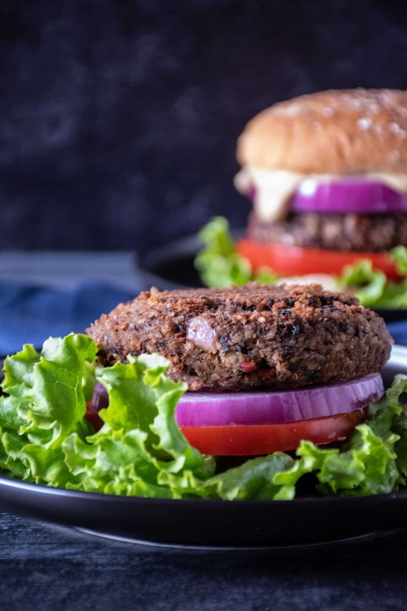 Plain bean burger on lettuce, with onion and tomato.