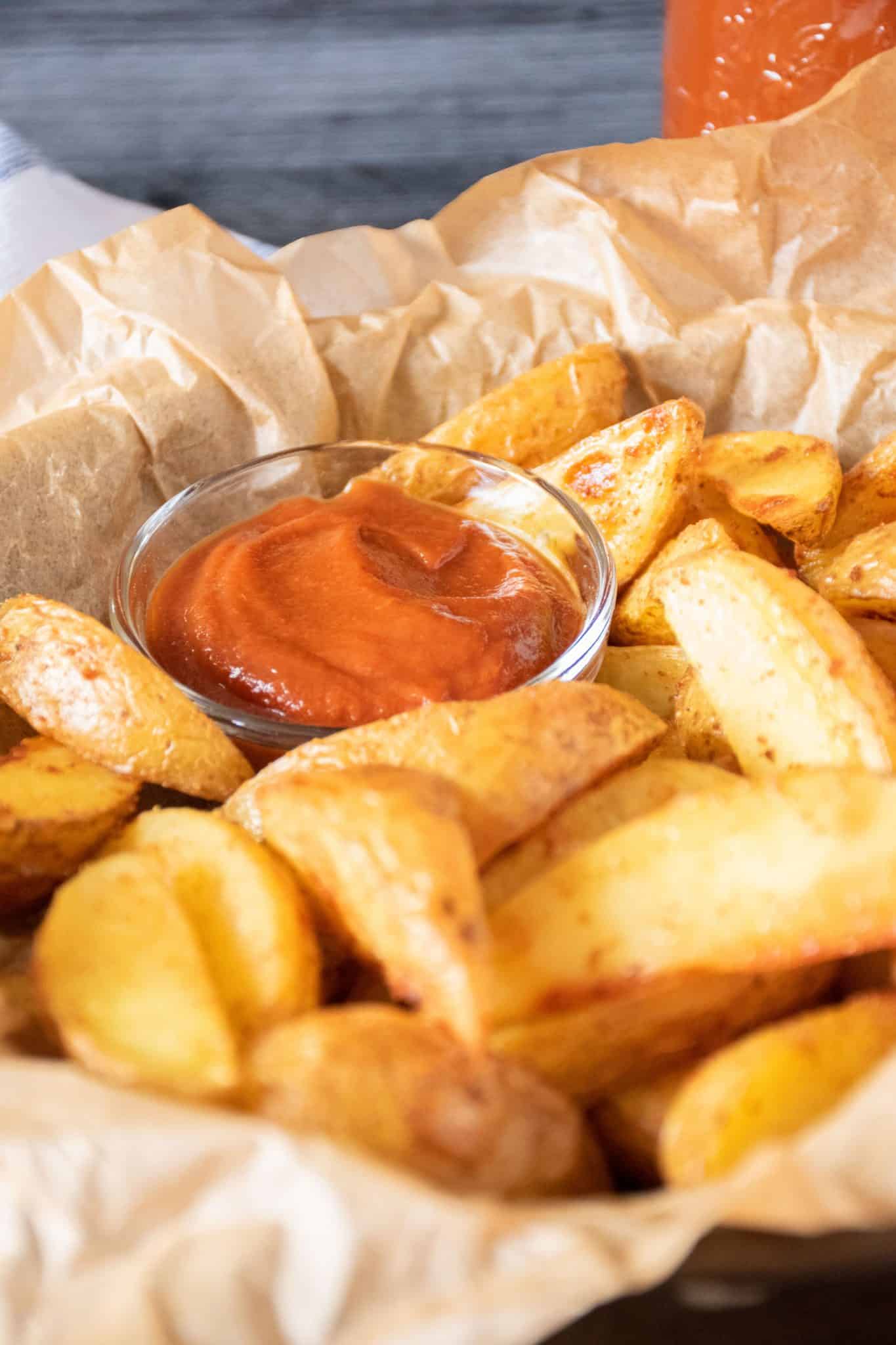 Basket of potato wedges with a small bowl of ketchup