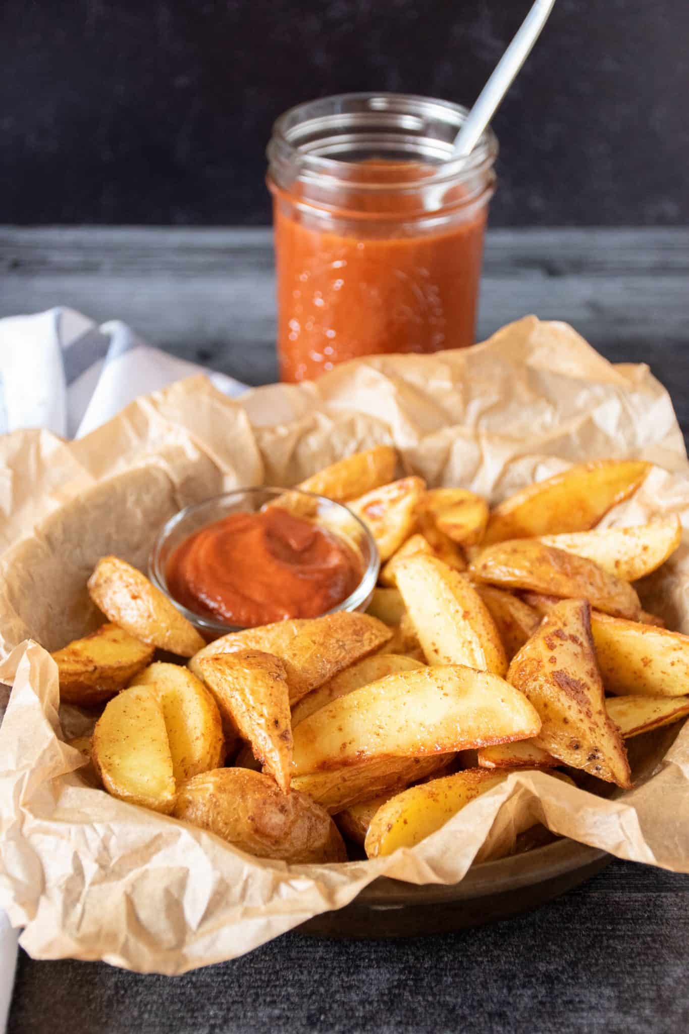 Basket of potato wedges with a small bowl of ketchup.