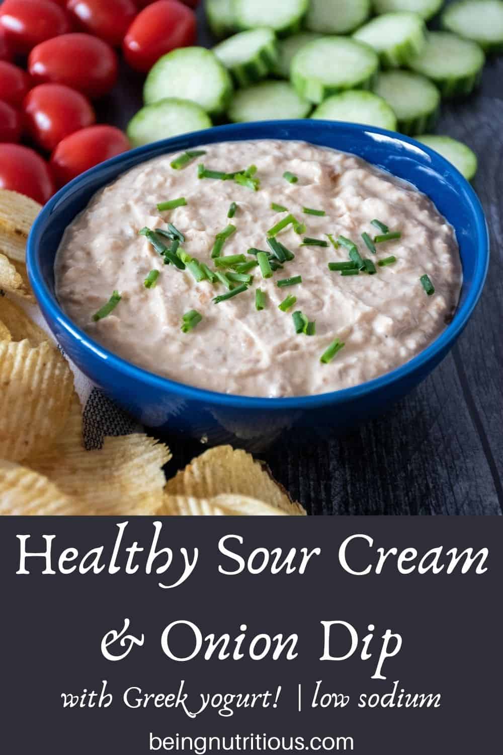 Bowl of dip, surrounded by chips, baby tomatoes, and cucumber slices. Text overlay: Healthy Sour Cream and Onion Dip, with Greek yogurt, low sodium.