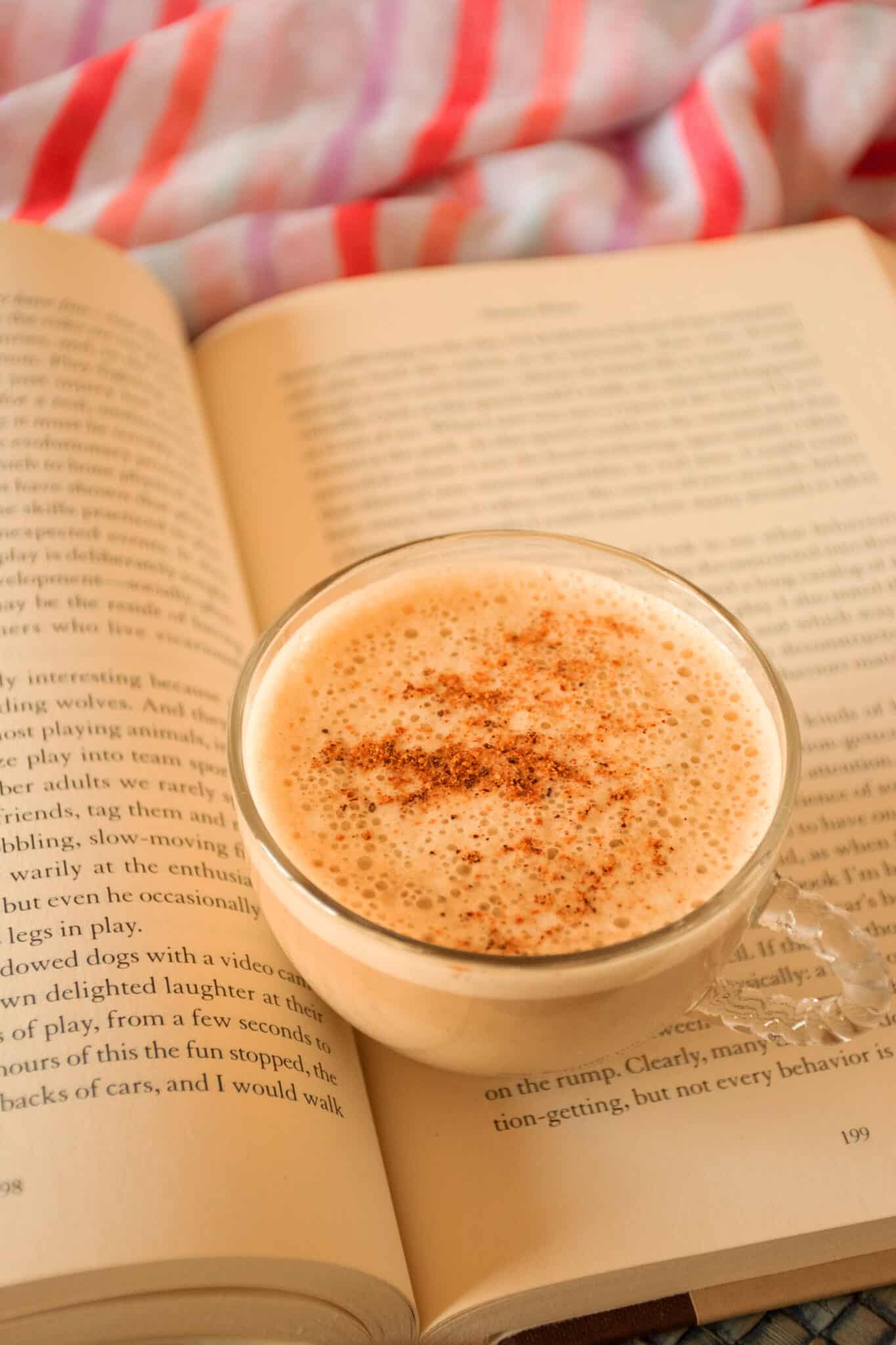 Small glass cup of latte sitting on an open book.