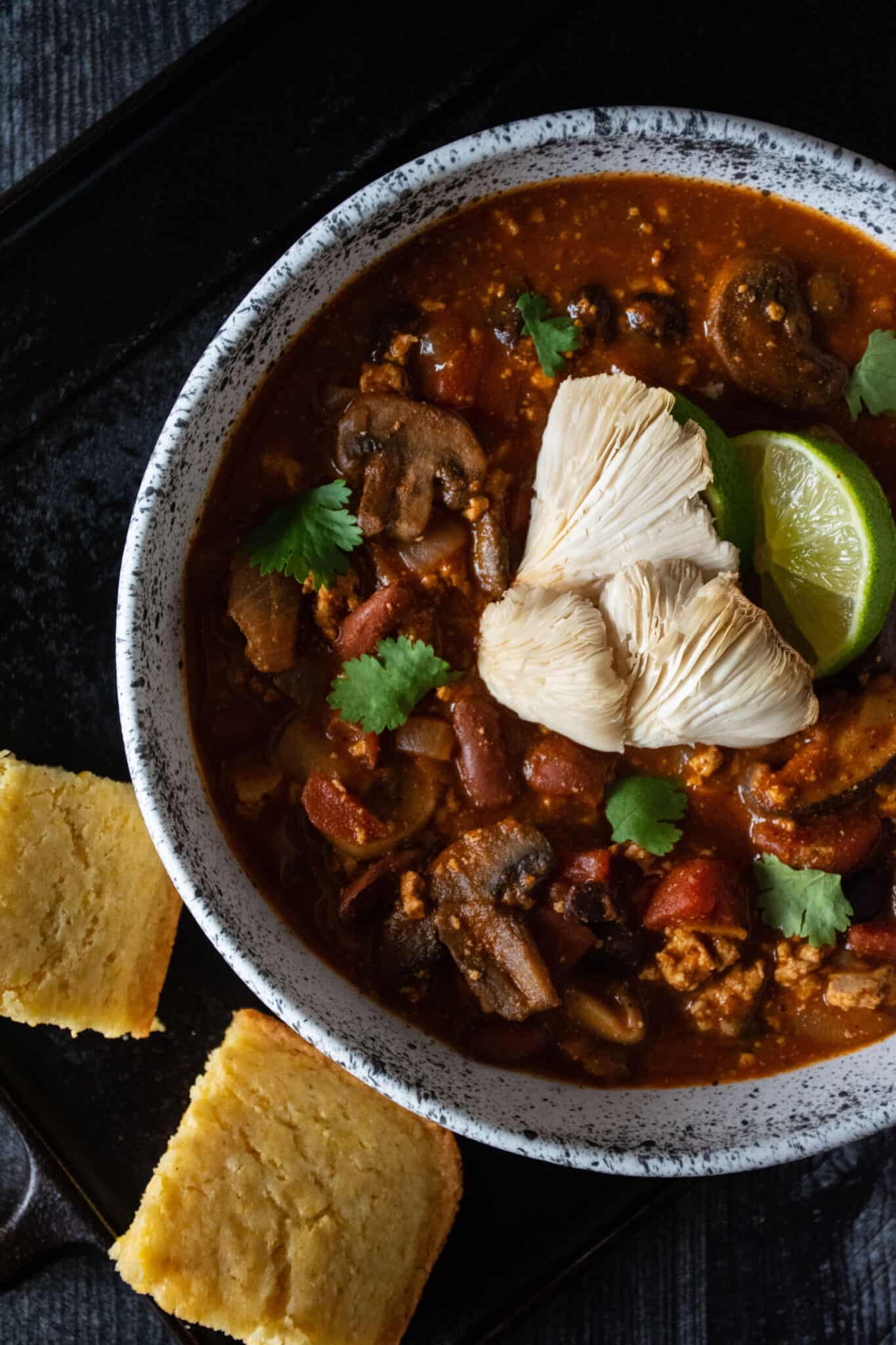 Overhead shot of a bowl of chili, with 2 squares of cornbread.