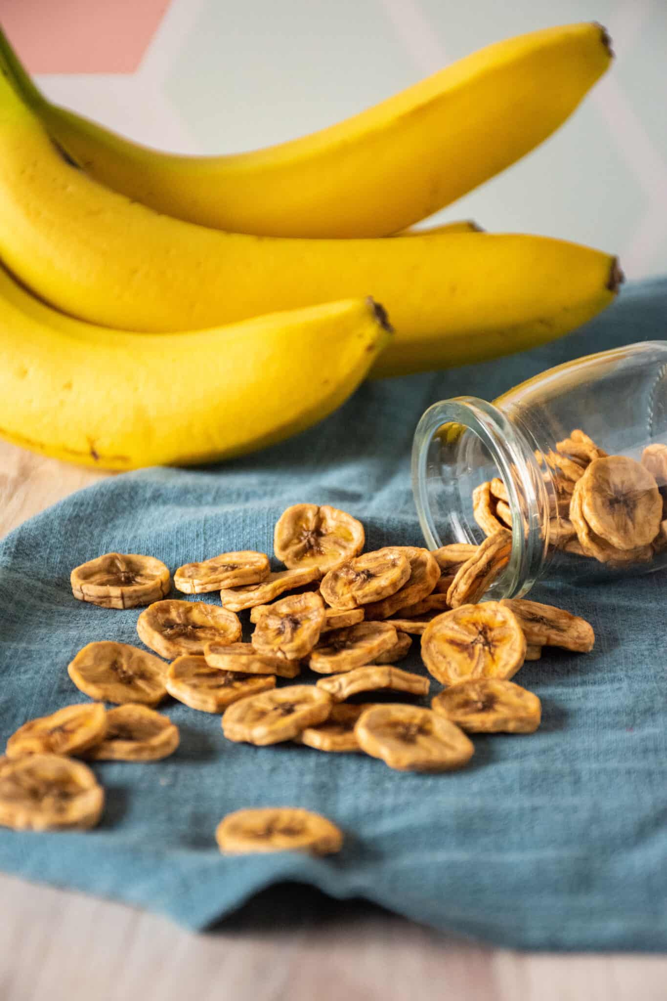 Dried banana chips spilling out of a glass jar