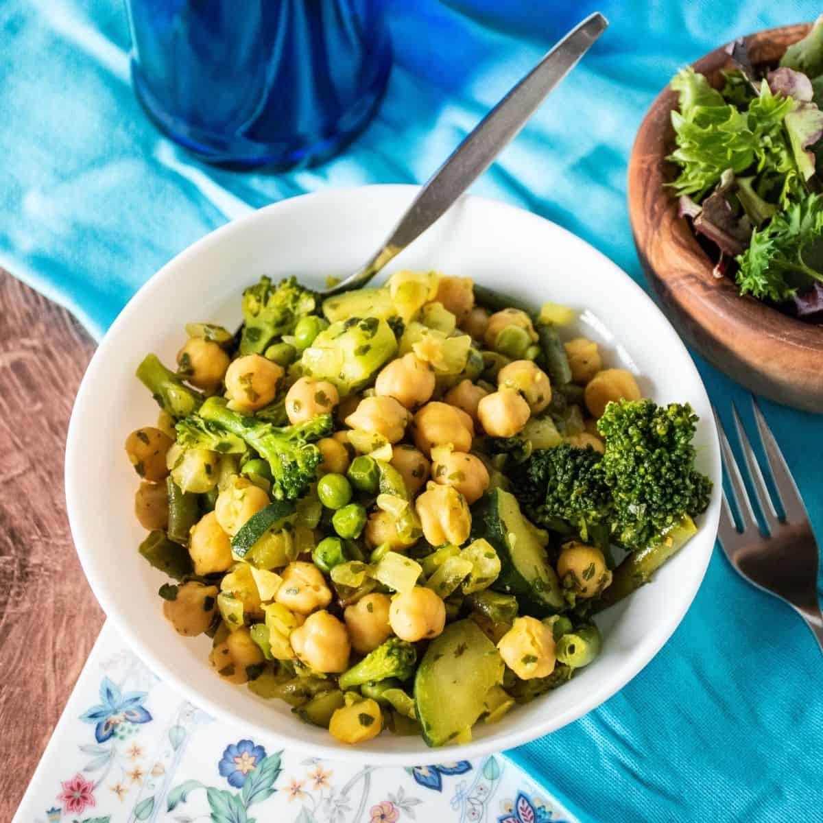Vegetable hash with chickpeas in a bowl with a salad to the side.