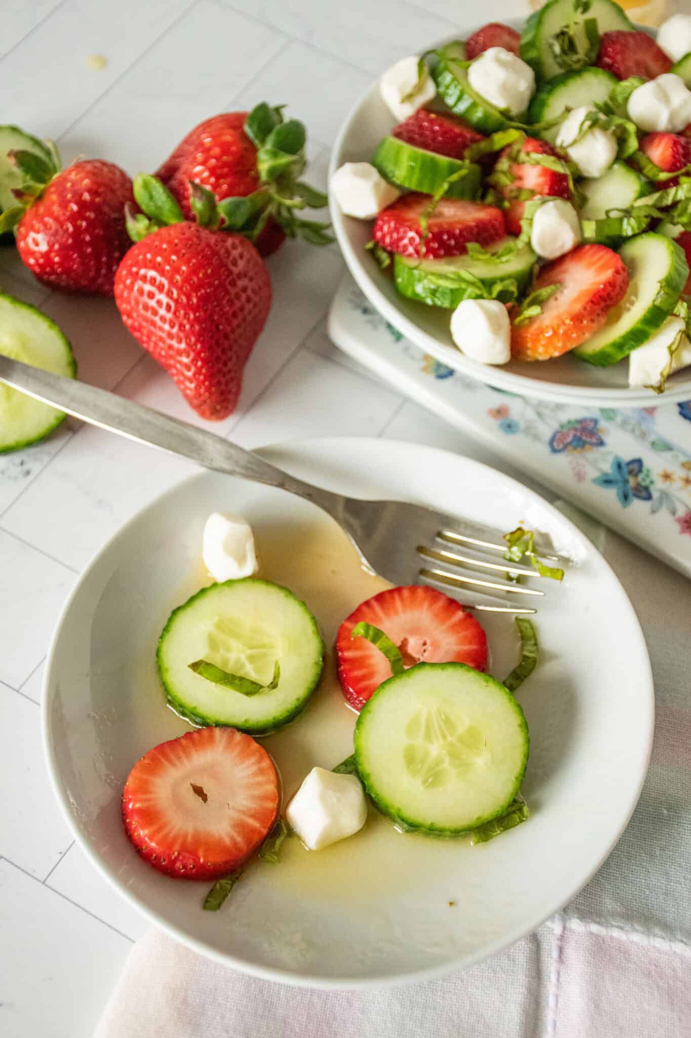 Cucumber strawberry salad with dressing, mostly eaten, on a plate.