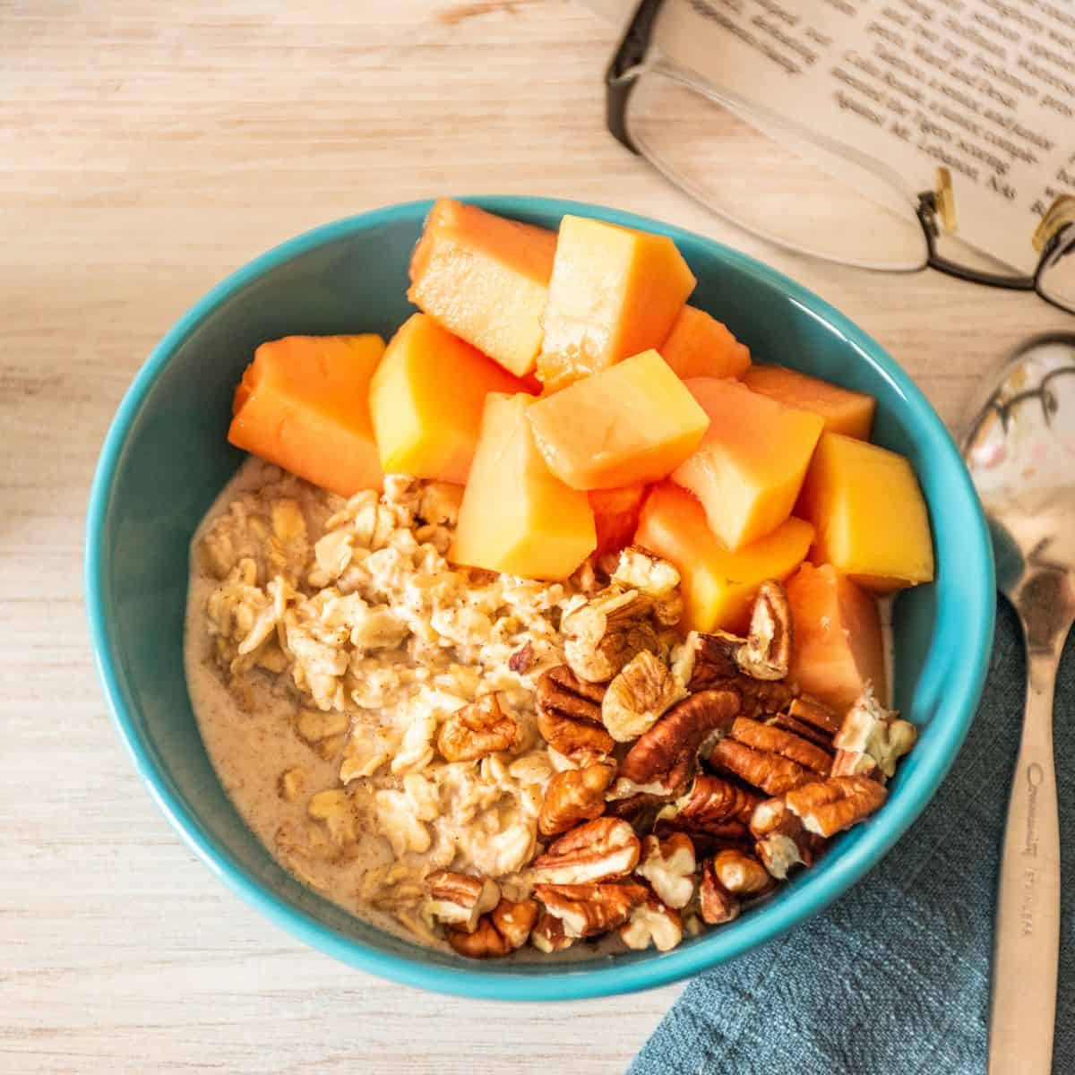 Overhead picture of a bowl of oats, with chopped pecans and papaya.