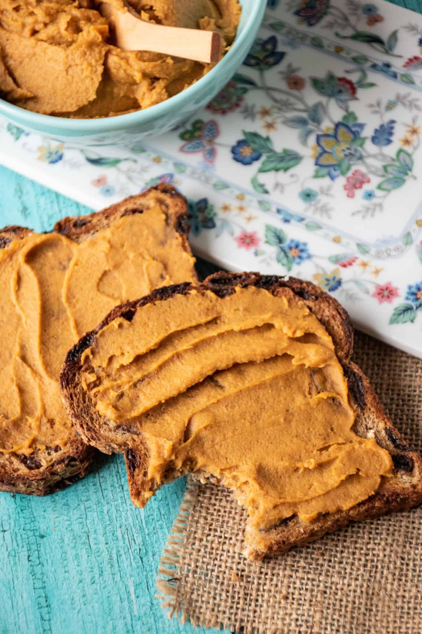 Two pieces of toast with a spread made of sweet potatoes and peanut butter. A bowl of the spread is partly visible at the top of the photo.