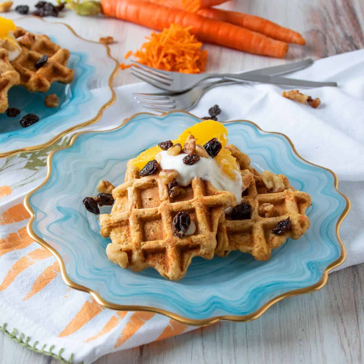 Plate of three small waffles, topped with yogurt, oranges, raisins, and walnuts.