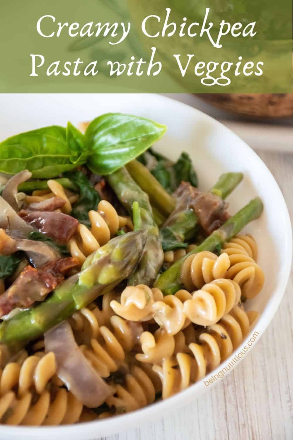 A bowl of creamy rotini pasta with vegetables. Text overlay: Creamy Chickpea Pasta with Veggies