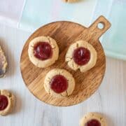 Overhead image of three thumbprint cookies on a platter with strawberry jam in them