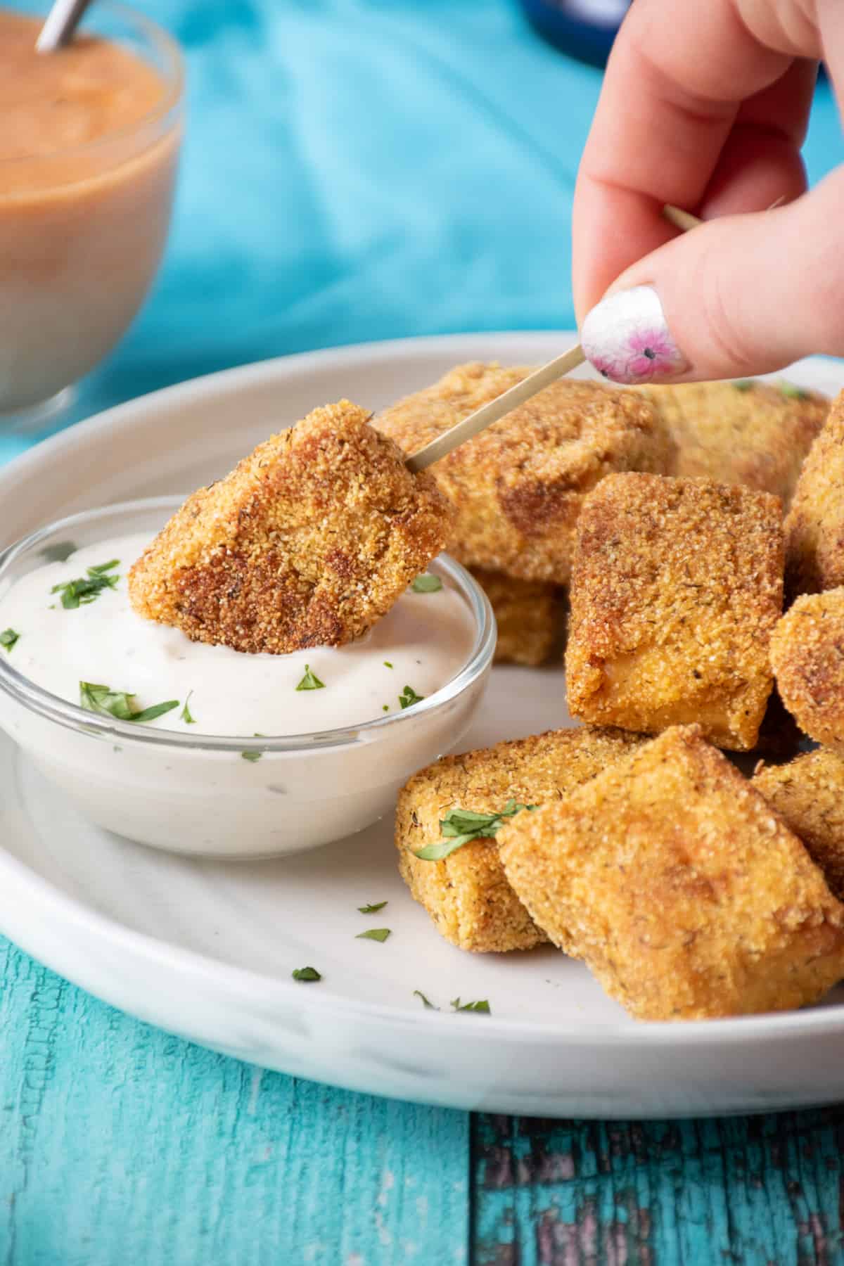 Tempeh appetizer being dipped into ranch dressing.