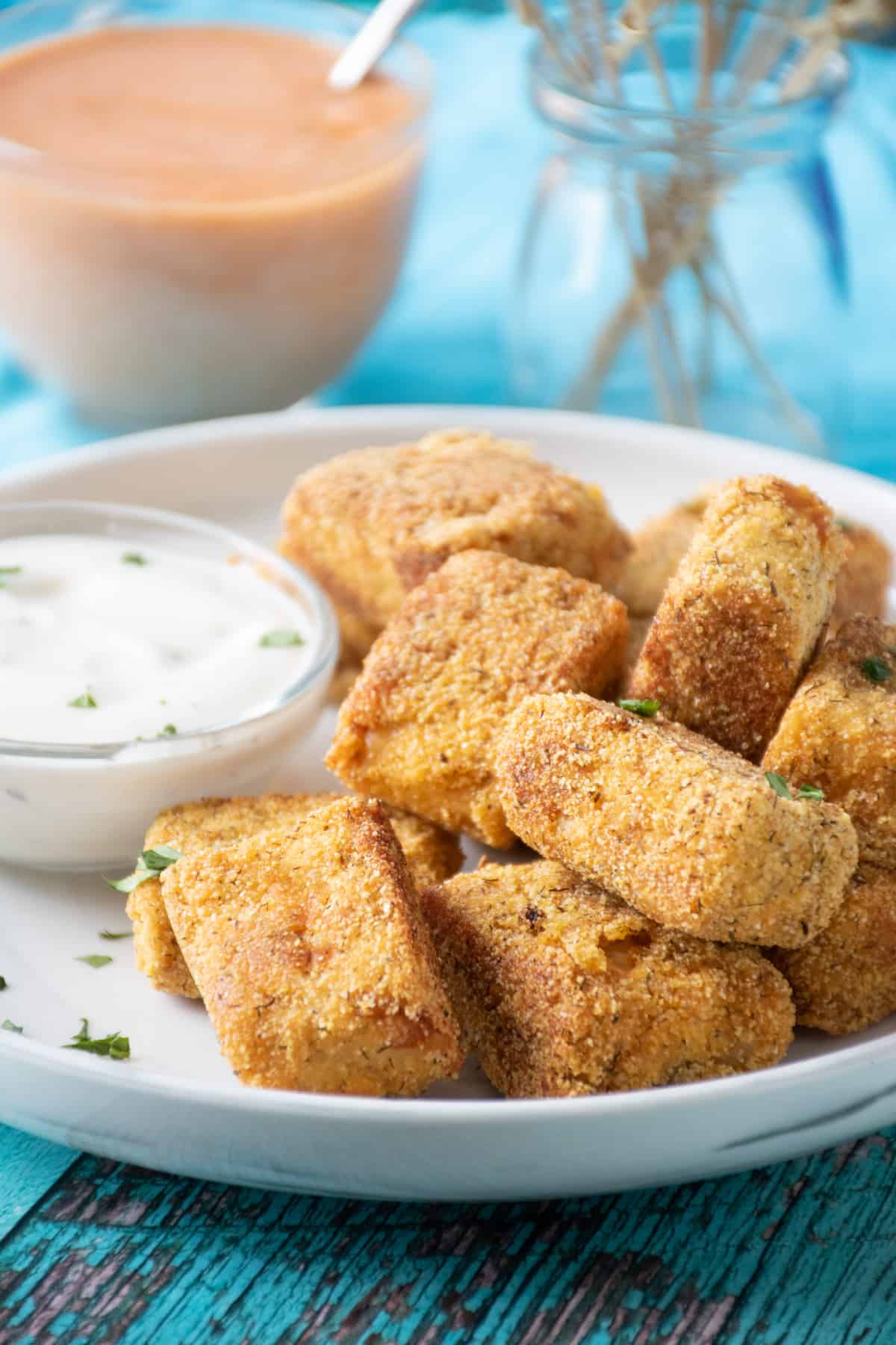 Crispy buffalo tempeh appetizers on a plate with ranch dressing in a small bowl.