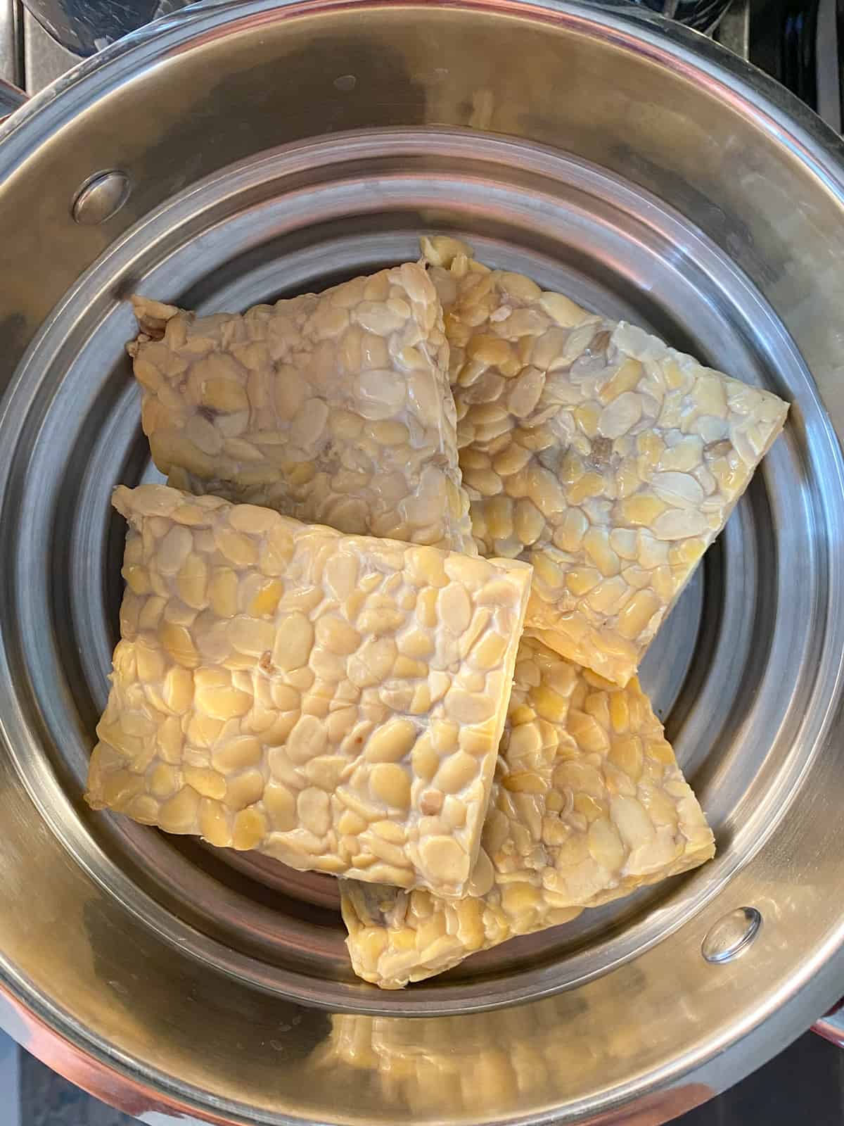 Steaming tempeh in a steamer pan.