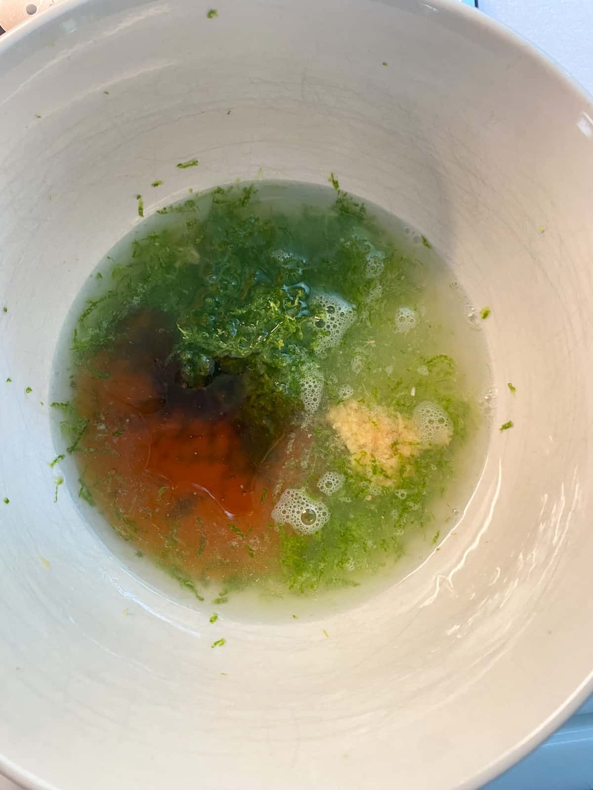 Ingredients for ginger lime dressing in a bowl.