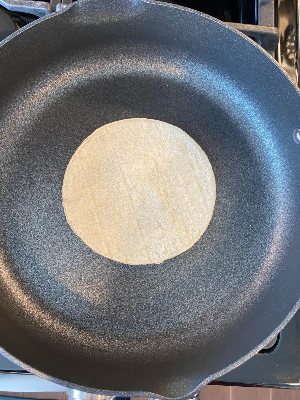 Corn tortilla in a skillet.