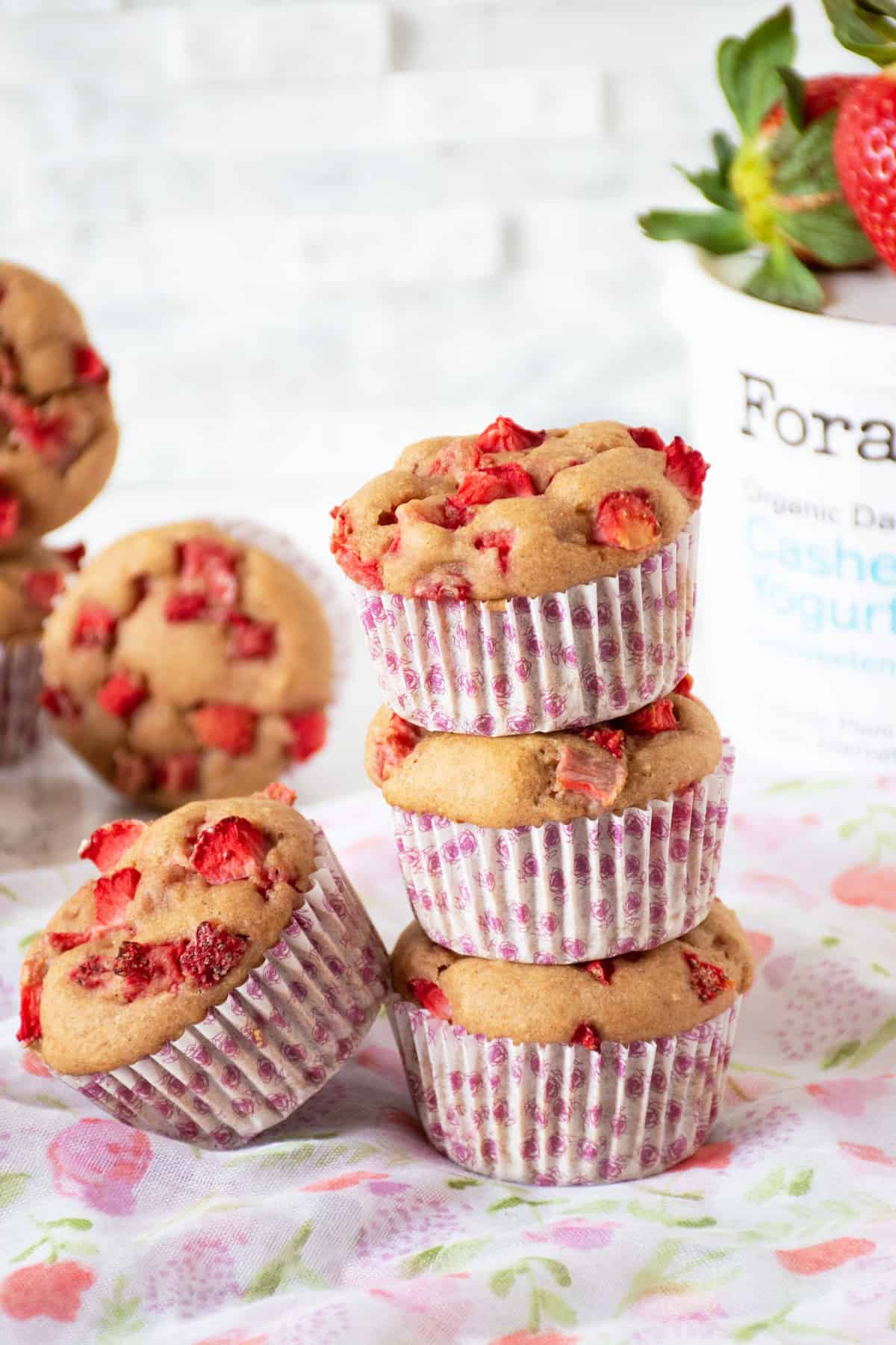 Stack of 3 muffins, with one additional muffin leaning against the stack. Tub of Forager Project Cashewmilk yogurt visible in the background.