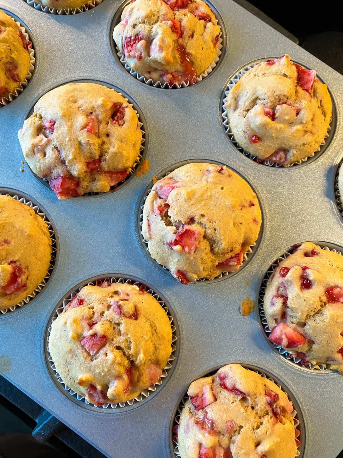 Baked strawberry muffins, in a muffin tin.