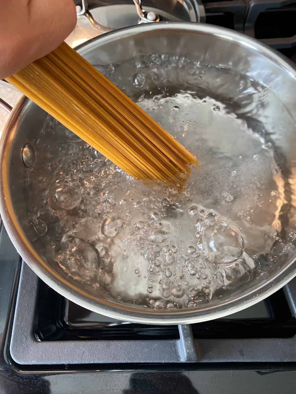 Dry spaghetti being lowered into a pot of boiling water.