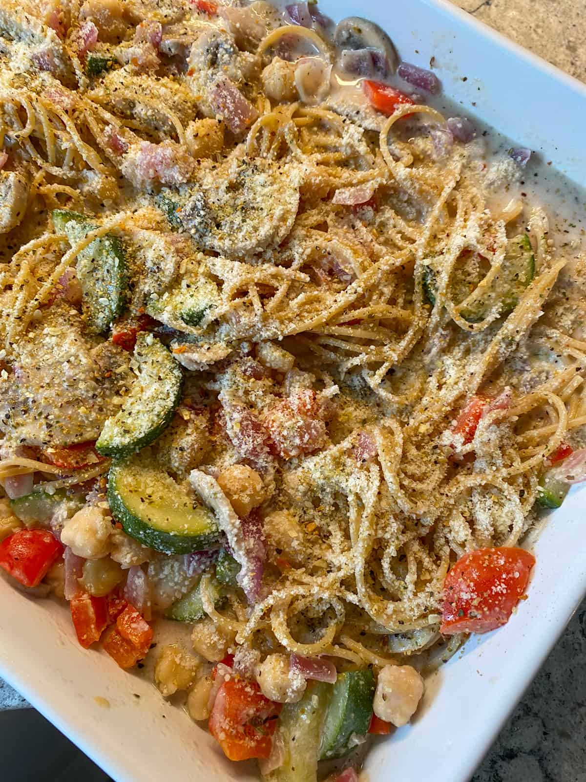 Unbaked tetrazzini, sprinkled with parmesan cheese and herbs.