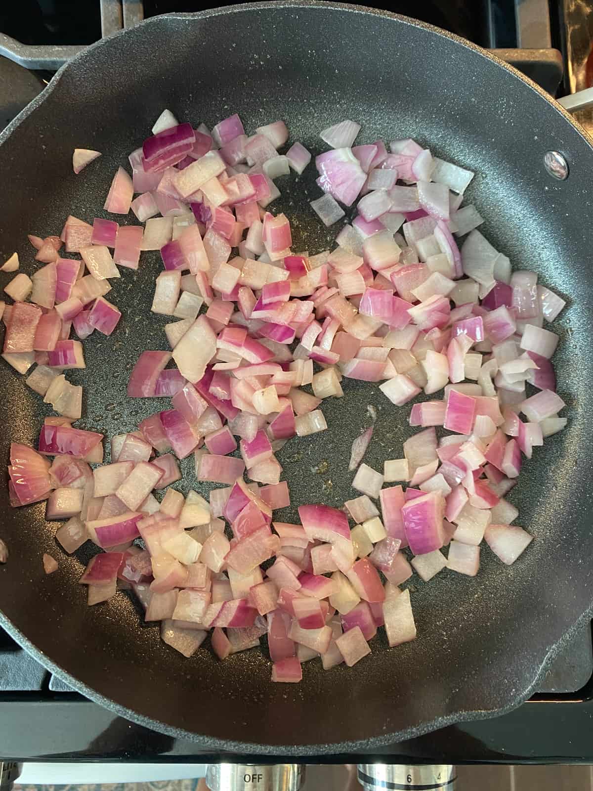 Chopped onions sautéing in a pan.