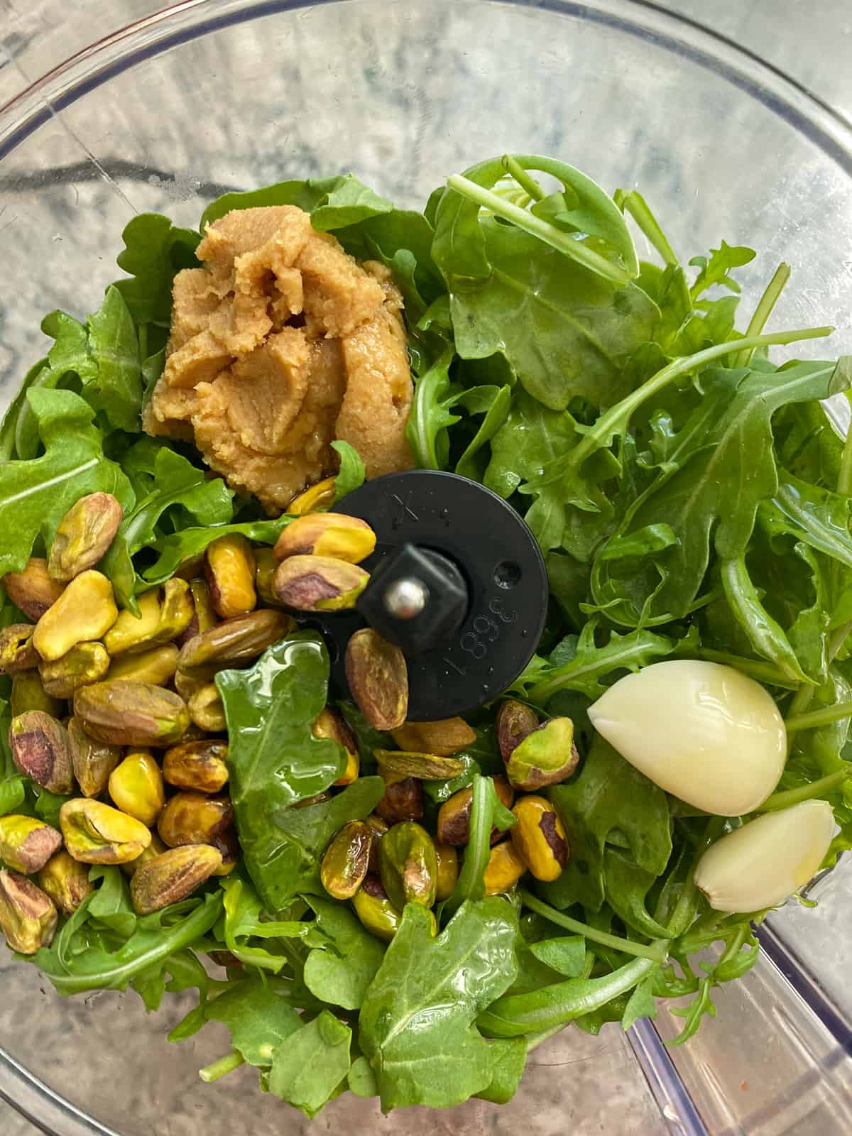 Ingredients for arugula pesto in a food processor, before processing.