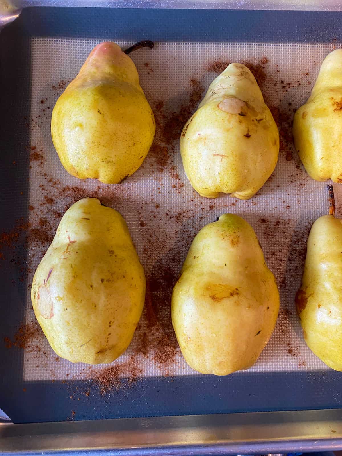 Halved pears, cut side down, on a baking sheet.