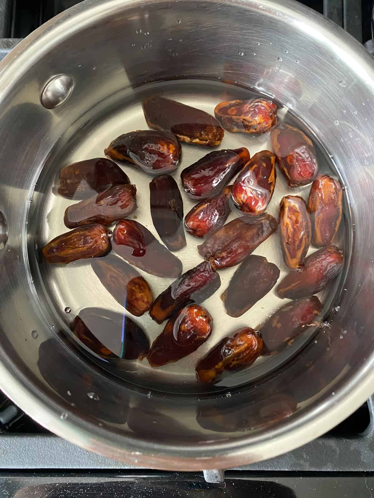 Whole dates soaking in a pan of water.