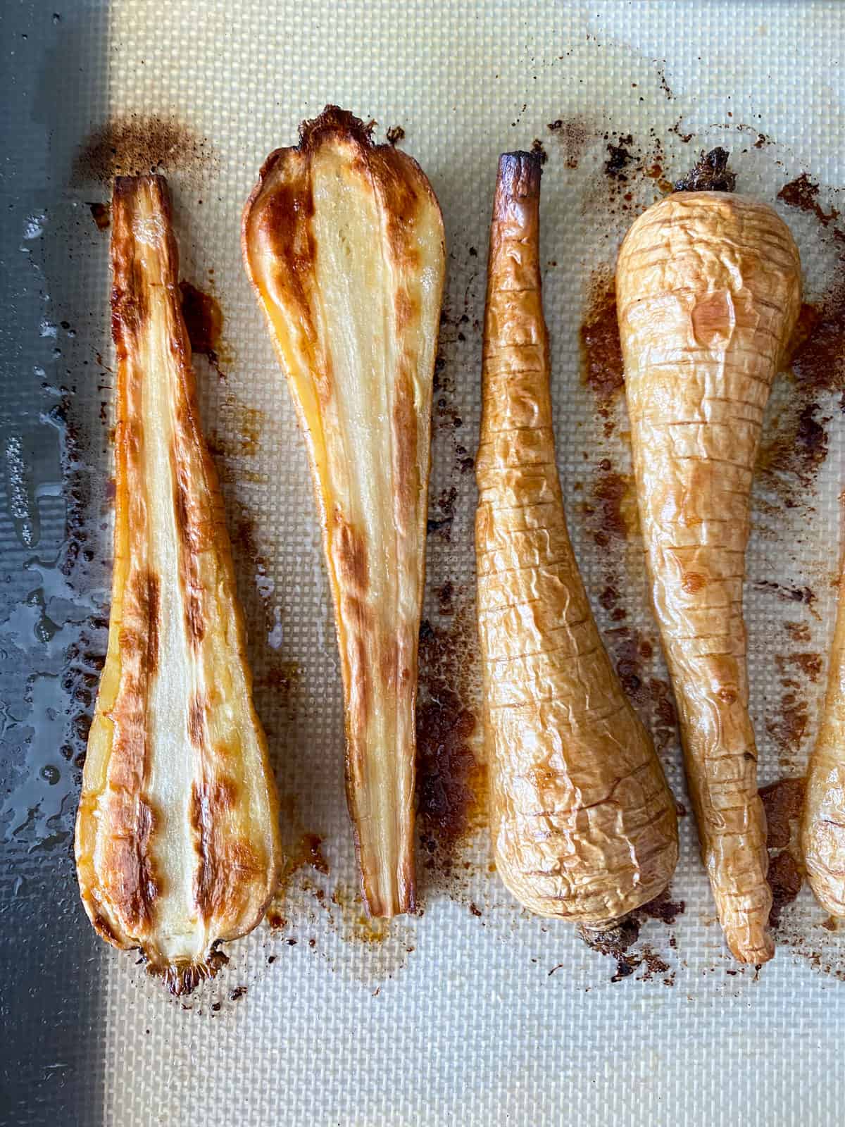 Completely roasted parsnips on a baking sheet.