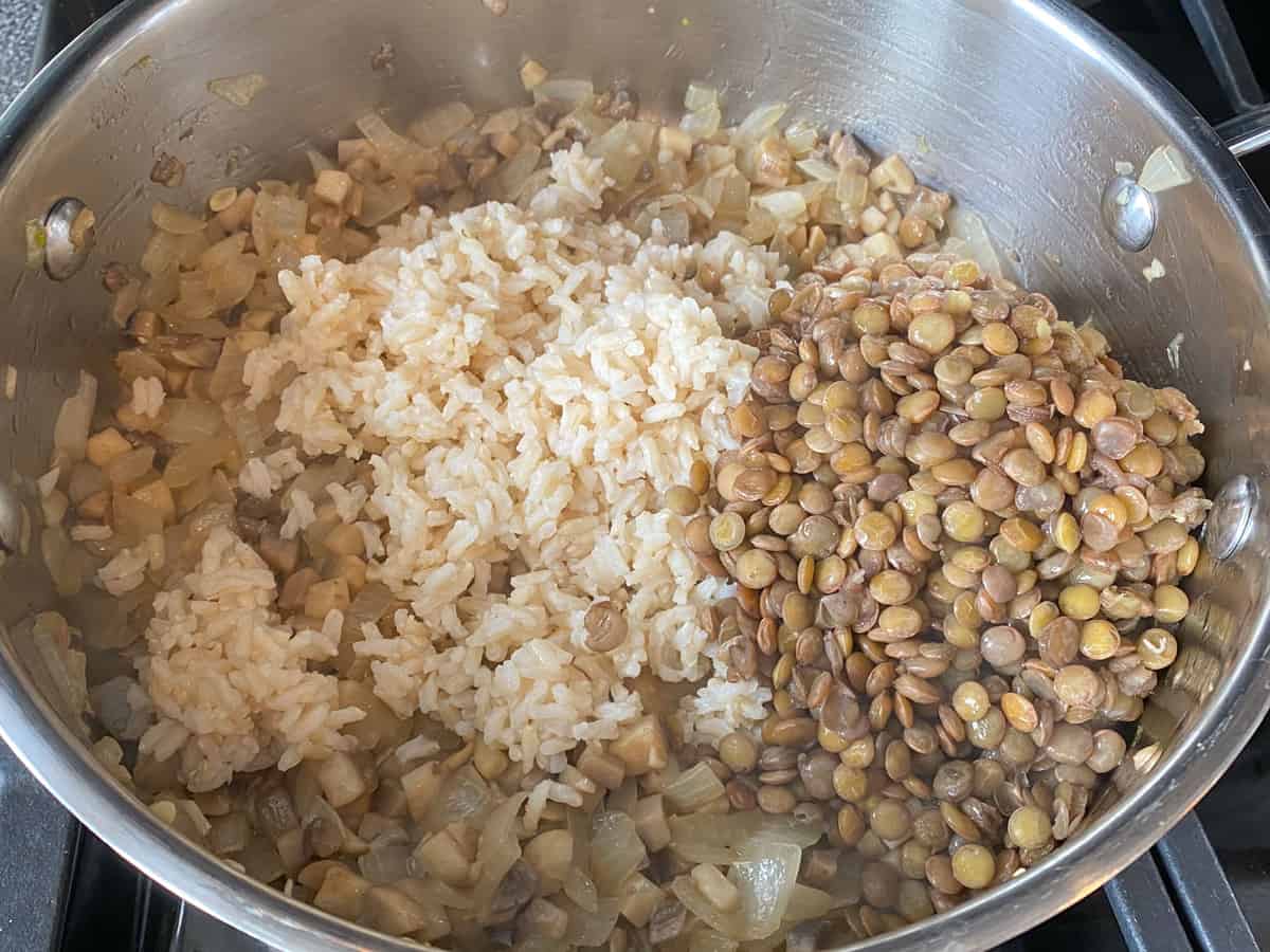 Cooked lentils and rice added to a large pan of filling for stuffed peppers.