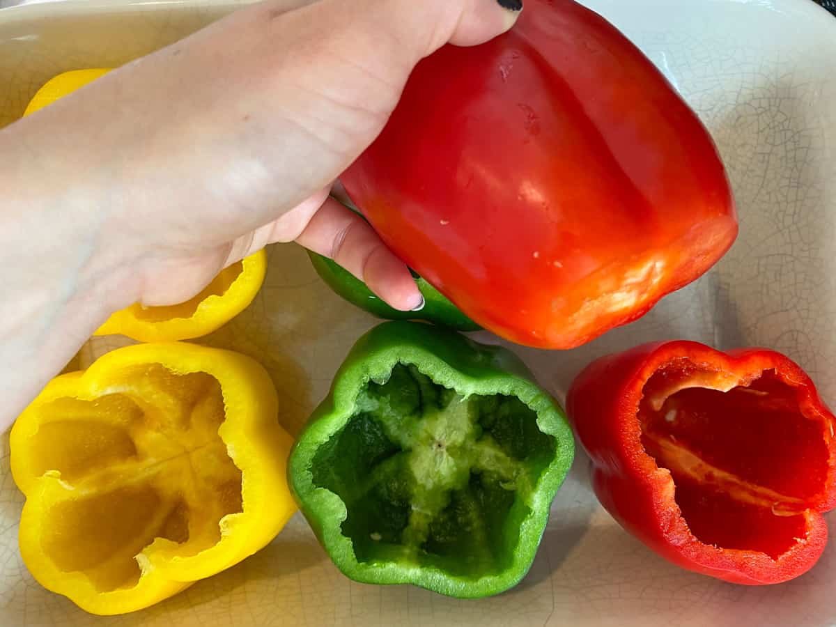 Holding up a bell pepper to demonstrate slicing part of the bottom off to make it sit level in the pan.