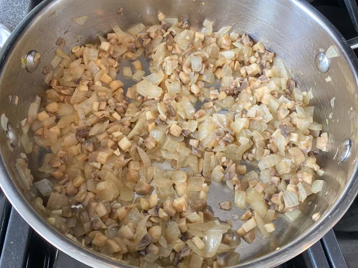 Sautéed onions and mushrooms in a pan.