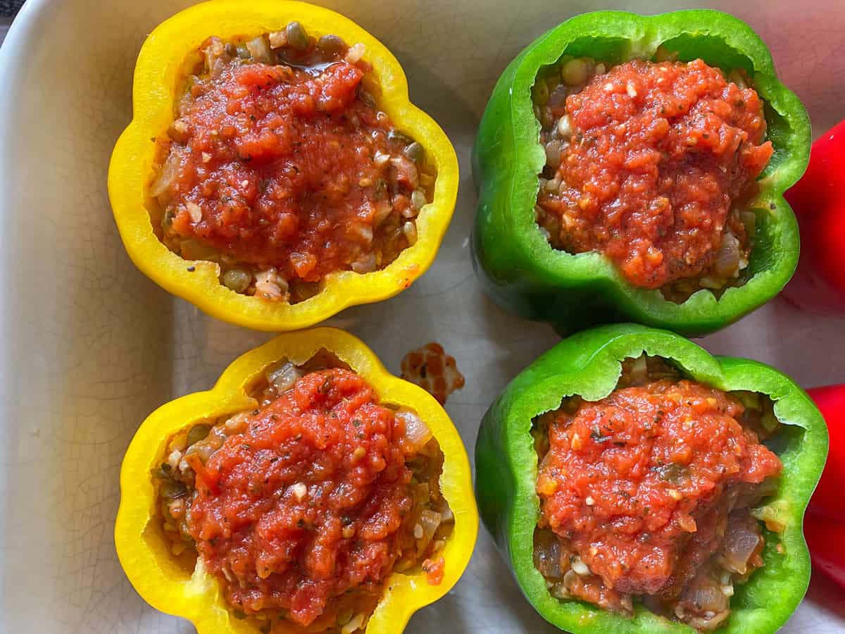 Marinara sauce spooned onto the top of stuffed peppers, just before baking.