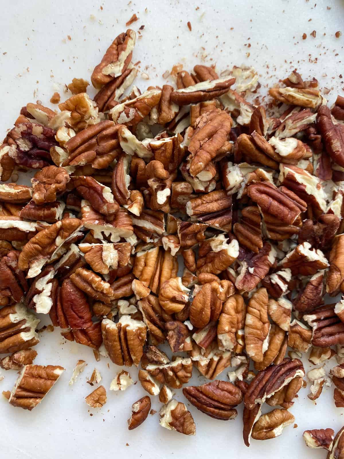 Roughly chopped pecans on a cutting board.