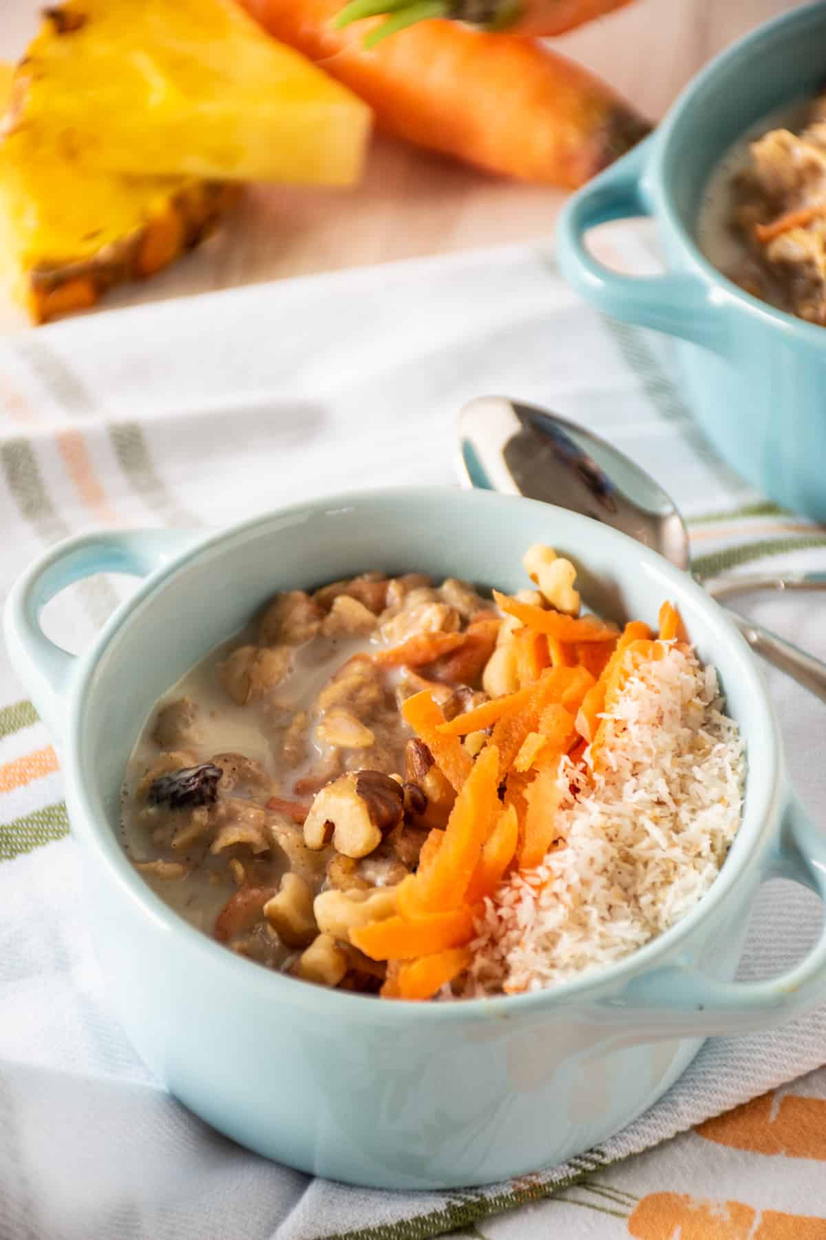 Oatmeal in a small bowl, garnished with walnuts, shredded carrots, and toasted coconut.