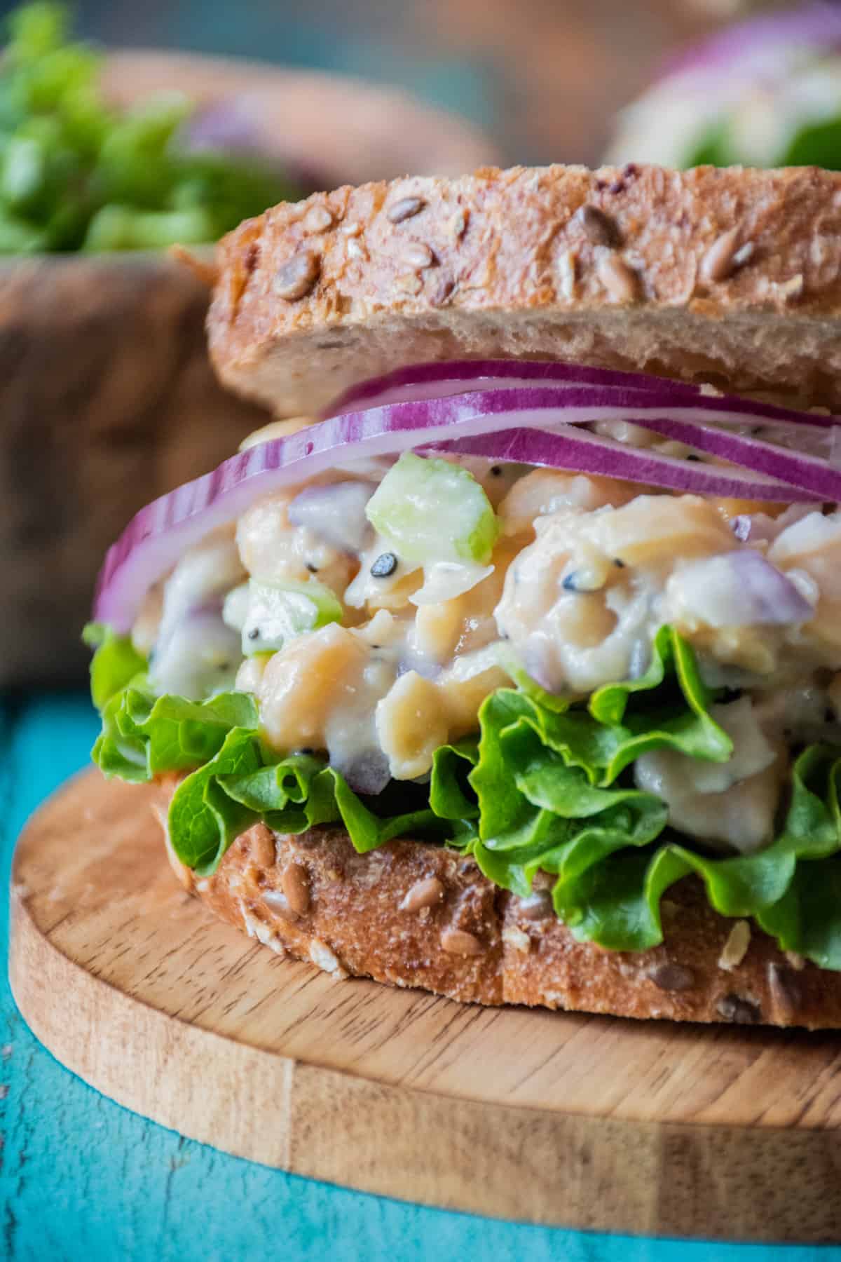 Close up of chickpea salad on a sandwich, with lettuce and red onion.